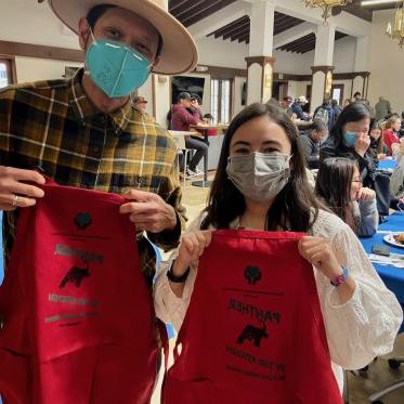 two people wearing masks and holding a red cloth