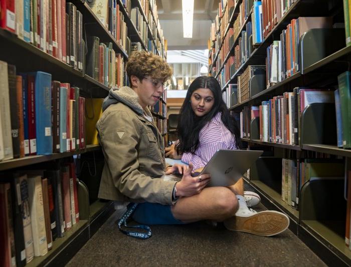 Students sitting in between rows of books studying